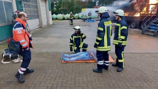 Eine gerettete Person wird erstversorgt – im Hintergrund die Brandsimulationsanlage.