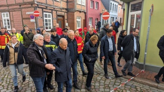 Bürgermeister Lutz Brockmann (vorne links) erläutert Bundeskanzler Olaf Scholz und Ministerpräsident Stephan Weil die Lage im Verdener Fischerviertel.