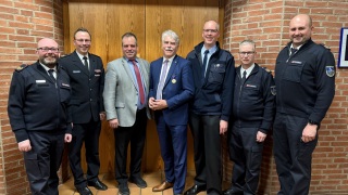 Zur Ehrung gratulieren Bürgermeister Lutz Brockmann (Mitte) und Dirk Wilkens (Mitte rechts) Kreisbrandmeister Dennis Körte, Regierungsbrandmeister Tim Fritsche, Landrat Peter Bohlmann, stellvertretender Kreisbrandmeister Ulf Carstens und stellvertretender Kreisbrandmeister Mario Rosebrock (v.l.).
